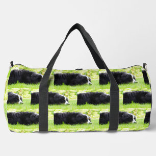 bernese mountain dog laying in grass duffle bag