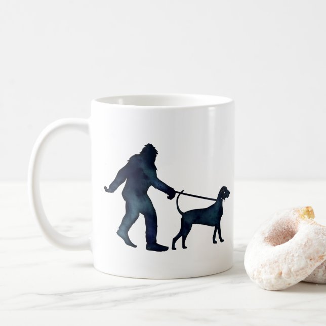 Bigfoot Walking a Bluetick Coonhound on a Leash Coffee Mug (With Donut)