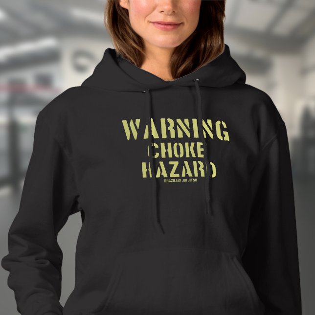 BJJ Warning Choke Hazard Brazilian Jiu Jitsu Hoodie (Choke hazard woman's black hoodie worn by a female model in a gym.)