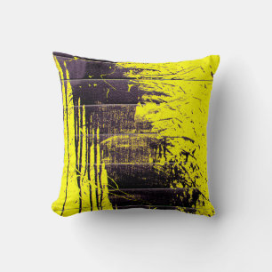 Black abstract splatter paint drips on a bright ye cushion