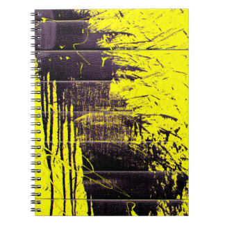 Black abstract splatter paint drips on a bright ye notebook