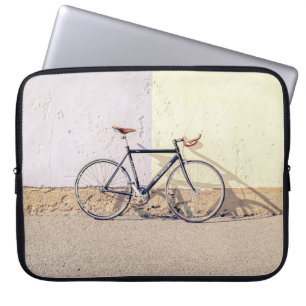 BLACK AND GRAY CITY BIKE LEANING ON WHITE WALL LAPTOP SLEEVE