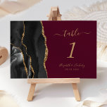 Black Gold Agate Burgundy Wedding Table Number<br><div class="desc">The left-hand edge of this elegant modern wedding table number card features a black watercolor agate border trimmed with faux gold glitter. The customisable text combines gold coloured handwriting,  and italic and copperplate fonts on a burgundy background.</div>