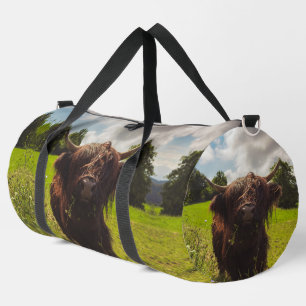 Black highland cow grazing green field sun light duffle bag