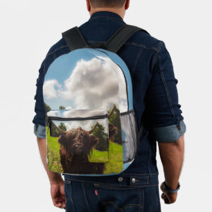 Black highland cow grazing green field sun light printed backpack