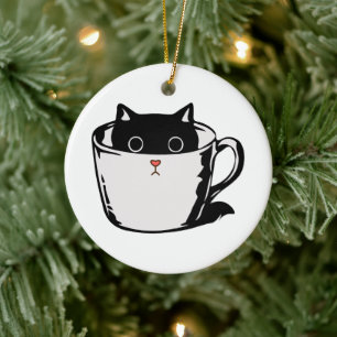 Black kitten with red nose hiding in a cup ceramic ornament