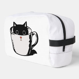 Black kitten with red nose hiding in a cup dopp kit