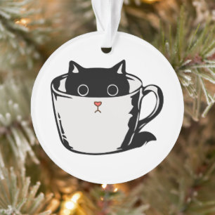 Black kitten with red nose hiding in a cup ornament
