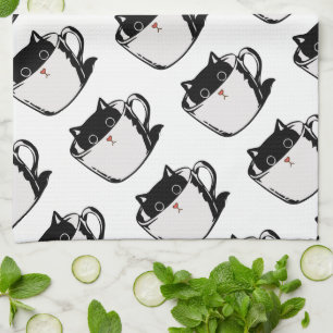 Black kitten with red nose hiding in a cup tea towel