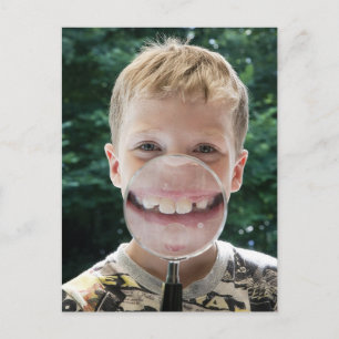 blonde boy behind magnifying glass smiling postcard