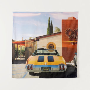 Blue car parked beside brown concrete building in tapestry