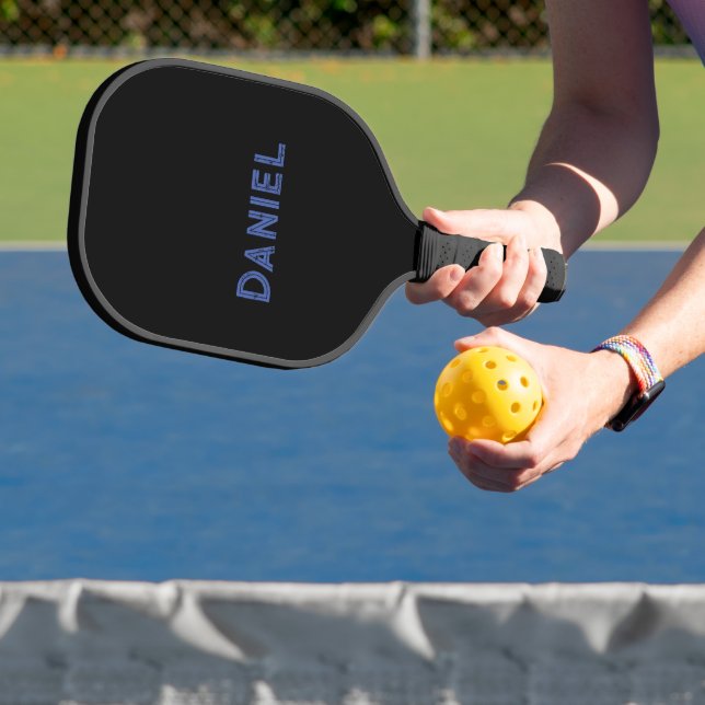 Blue custom name on black pickleball paddle (Insitu)