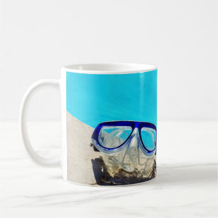 Blue framed swimming goggles near pool at daytime coffee mug