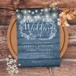 Blue Rustic Wood String Lights Script Wedding Invitation<br><div class="desc">A rustic wedding invitation featuring pretty string lights and a delicate hand-drawn rustic floral garland of botanical leaf foliage with stylish script typography,  on a blue rustic wood background. Personalize with your special wedding day information. Designed by Thisisnotme©</div>