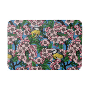Blue tit birds in the blooming cherry tree on blue bath mat