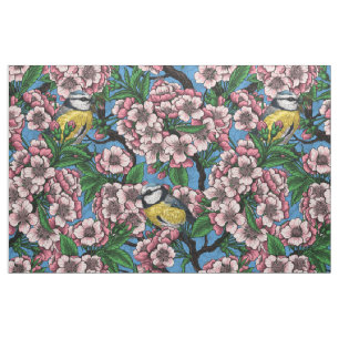 Blue tit birds in the blooming cherry tree on blue fabric