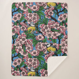 Blue tit birds in the blooming cherry tree on blue sherpa blanket