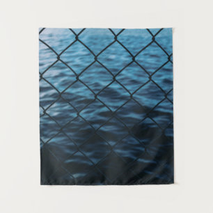 Body of water in front of chain link fence tapestry
