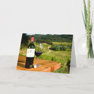Bottle of red wine and glass on table card