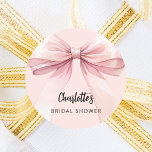 Bow pink Bridal Shower Classic Round Sticker<br><div class="desc">A blush pink coloured background. Decorated with a large bow.  Personalise and add the bride's name. Black handwritten style script.</div>