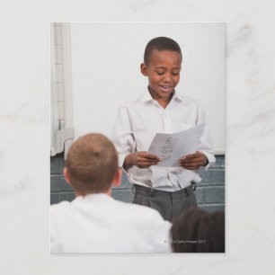 Boy standing in front of class reading in 2 postcard