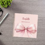 Bridesmaid blush pink bow notebook<br><div class="desc">A blush pink background colour. Decorated with a large pink bow.  Personalise and add your bridesmaid's name.  Golden handwritten style script.</div>
