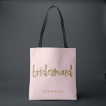Bridesmaid Gold Glitter Blush PInk Tote Bag<br><div class="desc">This Bridesmaid tote bag is perfect for busy bridesmaids to tote around all their belongings at the bridal shower or the main event. This blush pink tote bag features faux gold glitter style lettering on the front. Personalise these totes with your wedding party member's name on the front and the...</div>