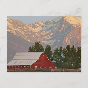 Bright red barn against Mission Mountains in Postcard