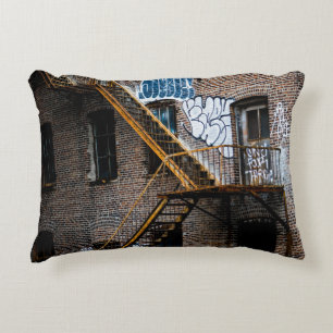 BROWN BRICK BUILDING WITH YELLOW METAL LADDER DECORATIVE CUSHION