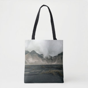 BROWN GRASS NEAR BODY OF WATER AND MOUNTAIN TOTE BAG