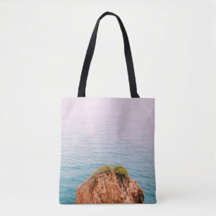 Brown rock mountain on body of water tote bag