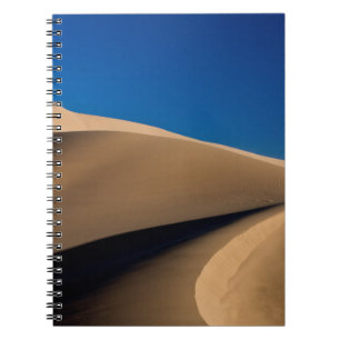 BROWN SAND UNDER BLUE SKY DURING DAYTIME NOTEBOOK