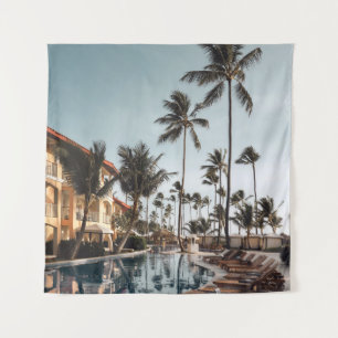 Brown wooden lounge chairs near pool surrounded by tapestry