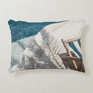 Brown wooden lounger near body of water decorative cushion