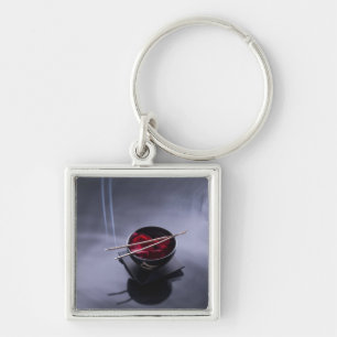 Burning incense on top of bowl of petals key ring