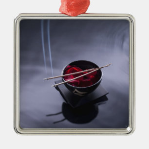 Burning incense on top of bowl of petals metal tree decoration