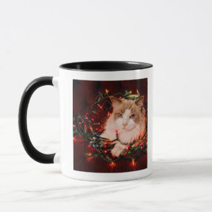 Cat sitting on a ball of Christmas lights. Mug