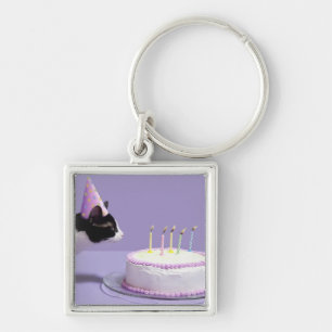 Cat wearing birthday hat blowing out candles on key ring