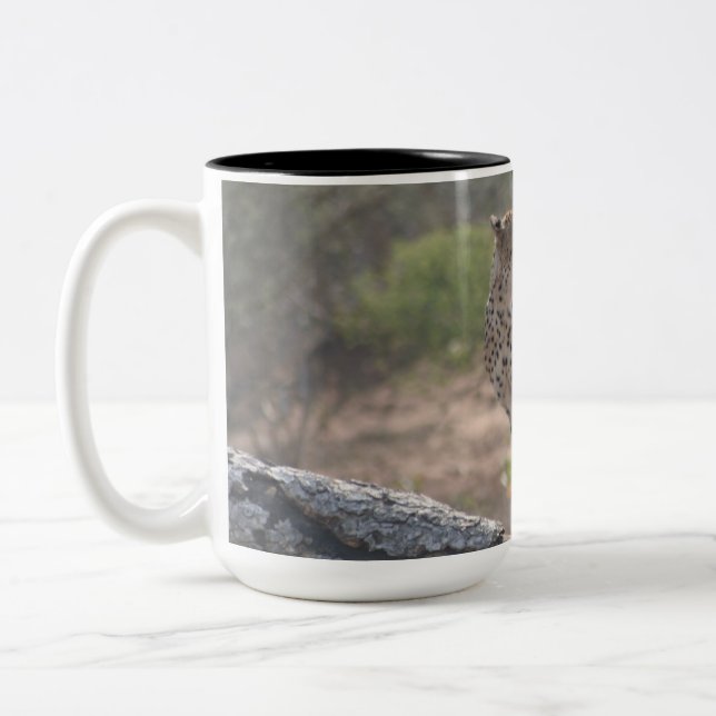 Cheetah sitting on a fallen tree in the wild  Two-Tone coffee mug (Left)
