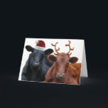 Christmas Cows in Santa Hat and Antlers Holiday Card<br><div class="desc">This dairy cow couple is all dressed up for the holiday season, and ready to pull Santa's sleigh on Christmas eve! A black steer wearing a red santa hat, and a brown coloured cow, wearing a pair of costume fuzzy antlers. Funny cow pun saying inside wishes family and friends a...</div>