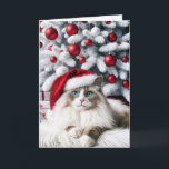 Christmas Ragdoll Cat In a Santa Hat Card<br><div class="desc">A fluffy Ragdoll cat with striking blue eyes wears a Santa hat sitting elegantly in front of a Christmas tree adorned with red and white ornaments</div>