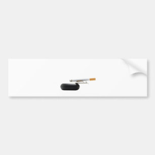 Cigarette on ashtray over white bumper sticker