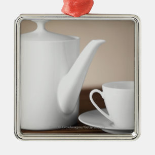 Close-up of a cup and a saucer with a tea kettle metal tree decoration