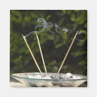 Close-up of burning incense sticks with pebbles magnet
