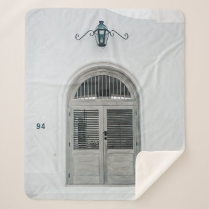 CLOSED GREY WOODEN DOOR BELOW BLACK LIGHT SCONCE SHERPA BLANKET