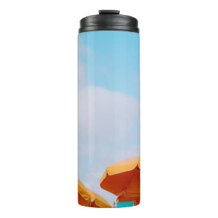 Closeup photo of lounger chairs and beach umbrella thermal tumbler