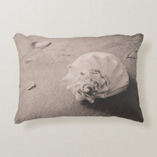 Closeup photo of white seashell on sand decorative cushion
