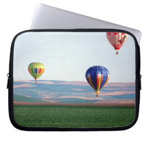 Colourful hot air balloons float over wheat laptop sleeve