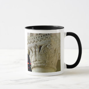 Column capital bearing symmetrically arranged grot mug