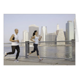 Couple running on pier with city in background
